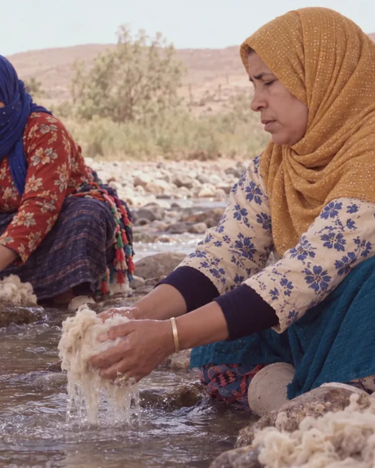 Trois artisanes lavent à la main de la laine de mouton dans une rivière de l’Atlas
