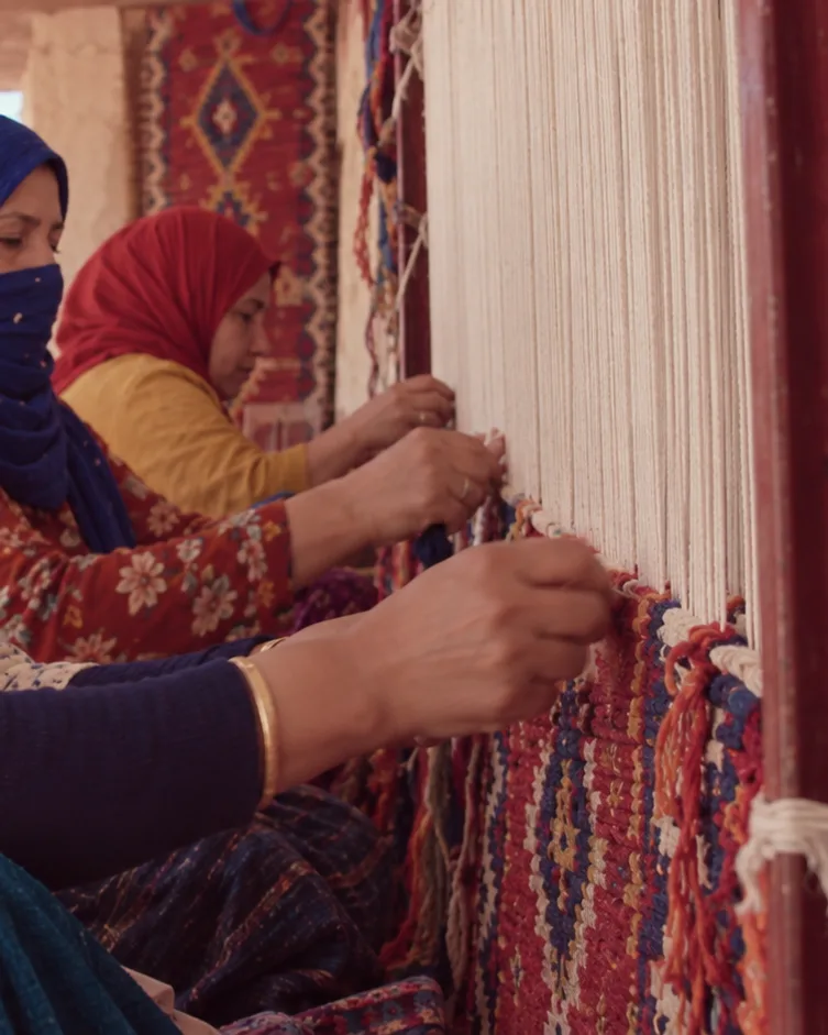 Mains de tisseuses nouant la laine sur un métier à tisser traditionnel